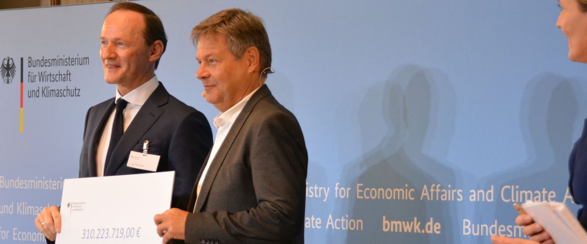 Das Bild zeigt Robert Habeck, der einen Klimaschutzvertrag an Dr. Uwe Liebelt, President Europäische Verbundstandorte, BASF SE, überreicht. 